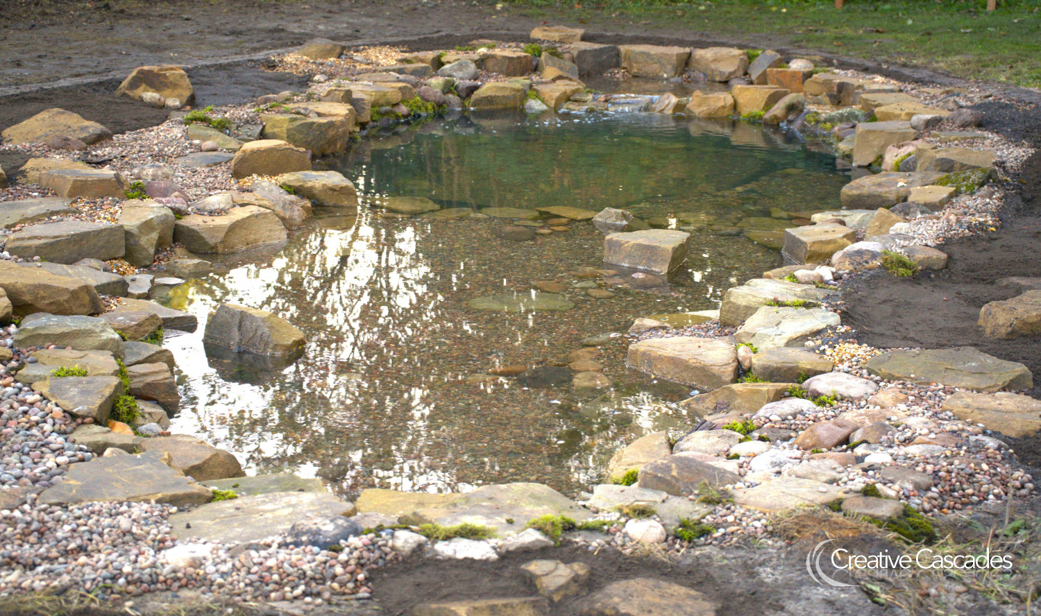Medium / large pond by us in Autumn 2023, the large shallow zone makes a great area for plants and wildlife and acts as a skimming zone to help leaves move into the intake bay for easy removal from one area.  - Landscaping and Water Features -  Creative Cascades