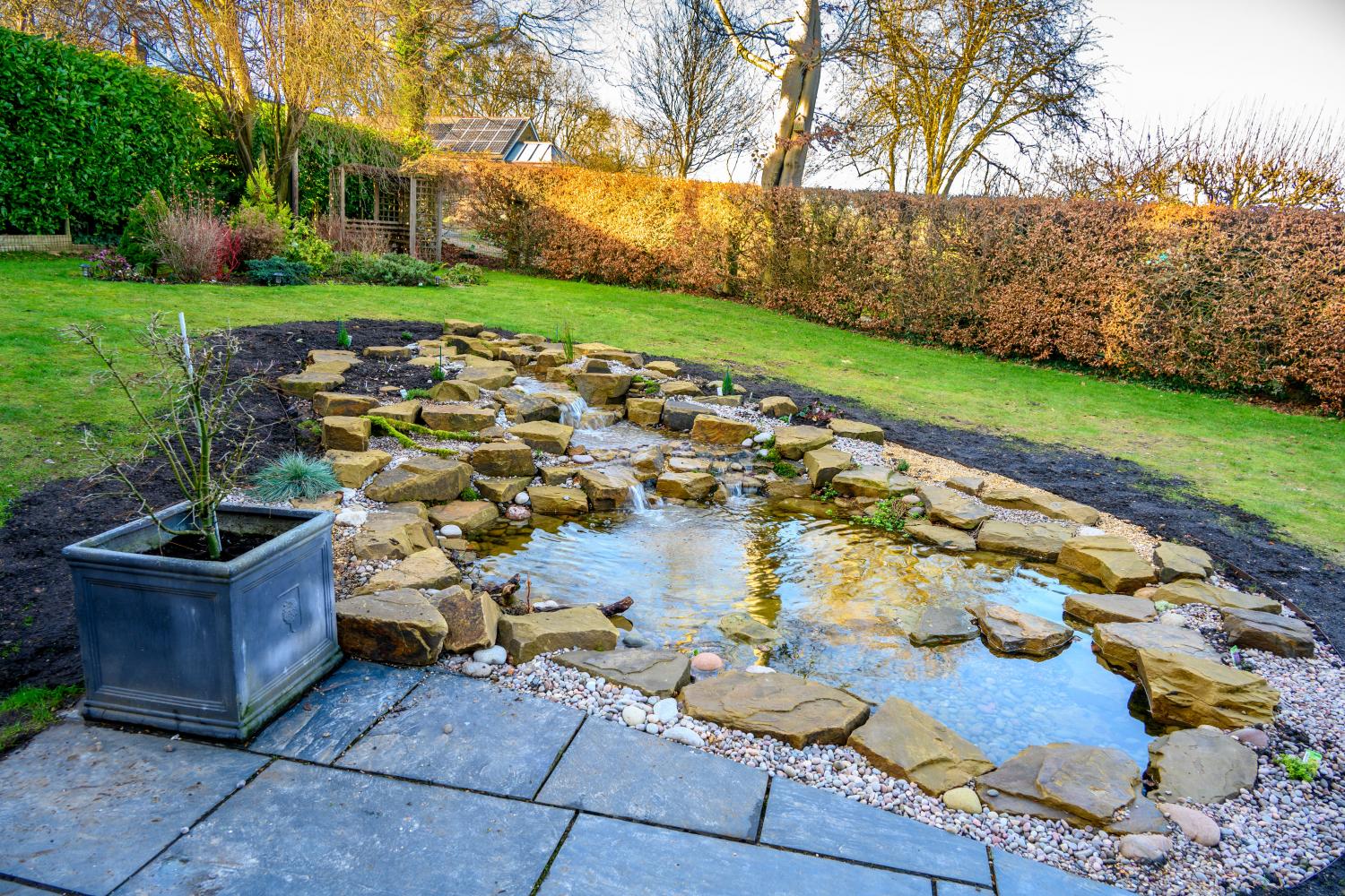 Pond using Yorkstone and Scottish pebbles. Once plant growth is in full swing, the rocky appearance will be considerably softened. Plenty of rocks required to retain the lawn and soil to the rear.  - Landscaping and Water Features -  Creative Cascades